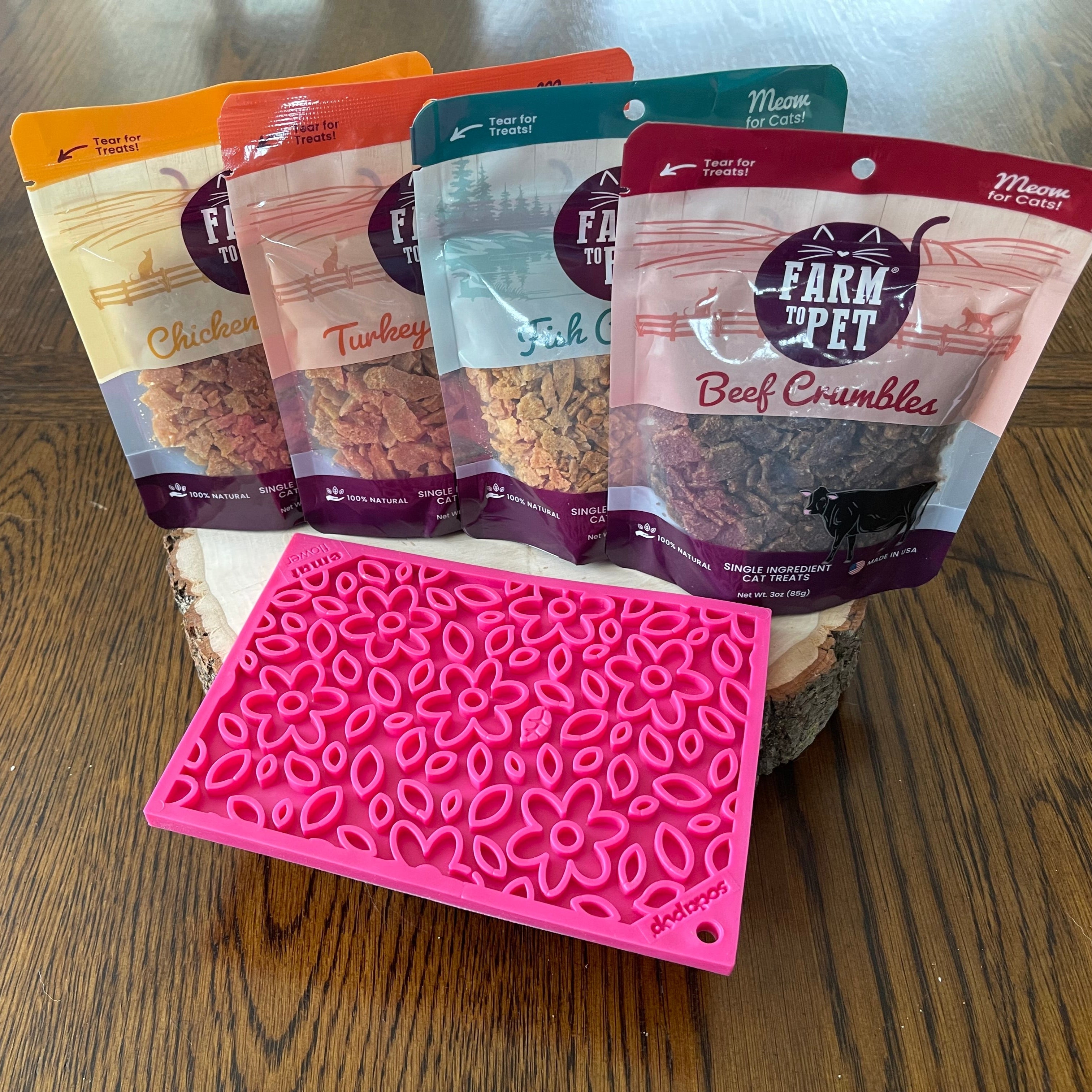 Assorted Farm to Pet crumbles pouches with a pink silicone feeding mat
