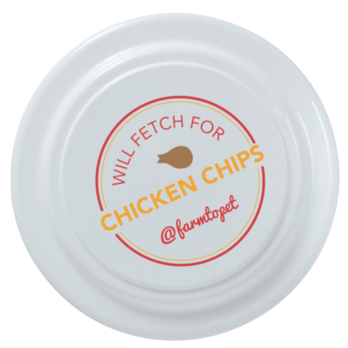 White dog frisbee with Chicken Chips Will Fetch For logo and @farmcoped