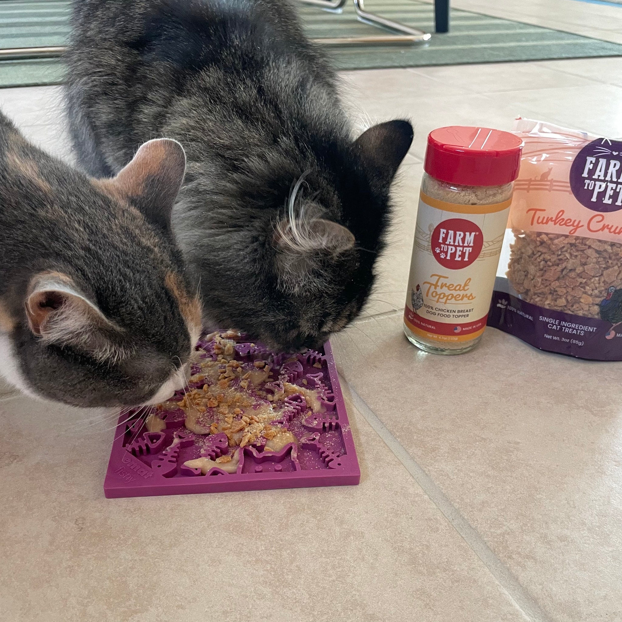Cat eating from a purple textured lick mat for cats and small dogs on tile floor