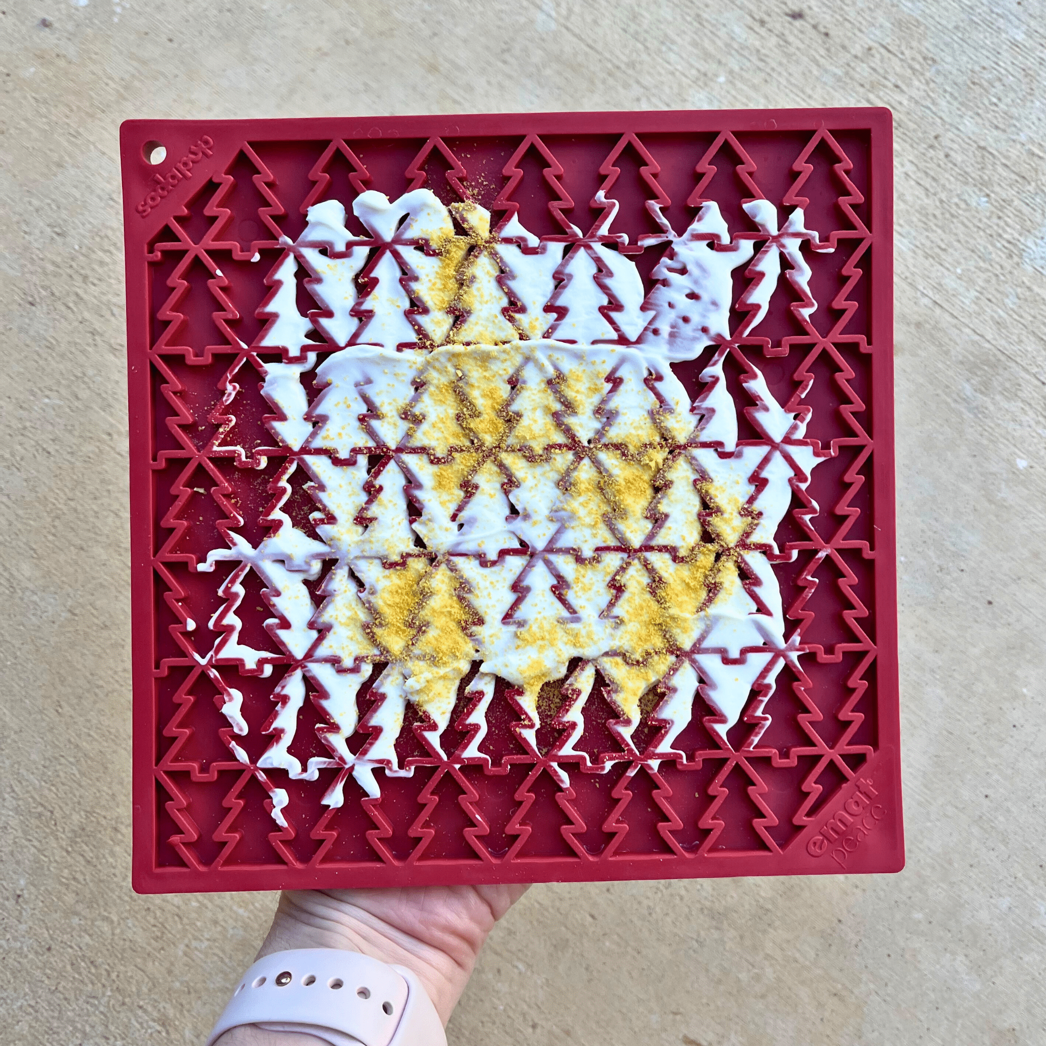 Red silicone lick mat with raised tree pattern holding smeared treats