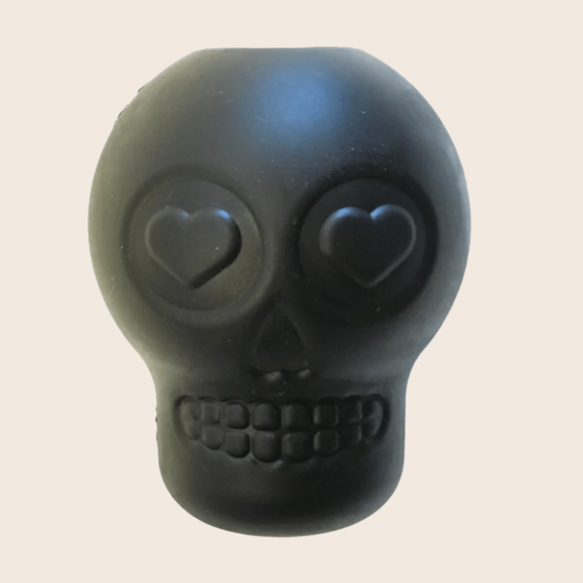 Skull-shaped dog treat dispenser, dark gray with heart-shaped eyes and ridged mouth.