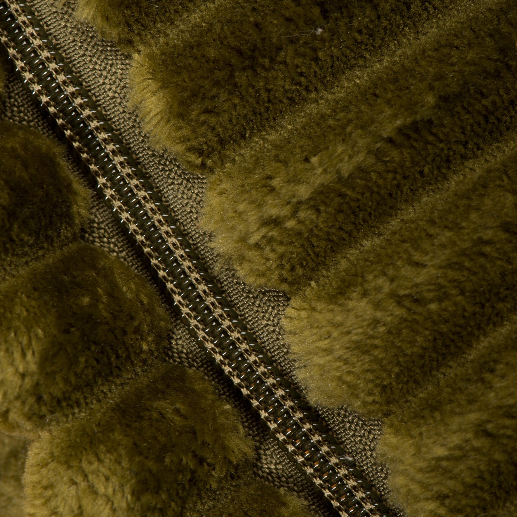 Olive green plush dog bed close-up showing zipper and stitched seam