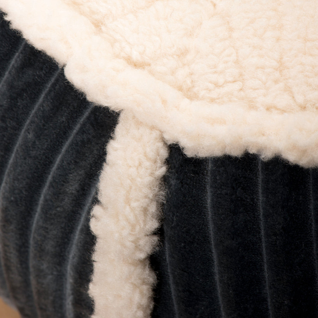 Bolster dog bed with dark fabric and thick white sherpa trim along the edge