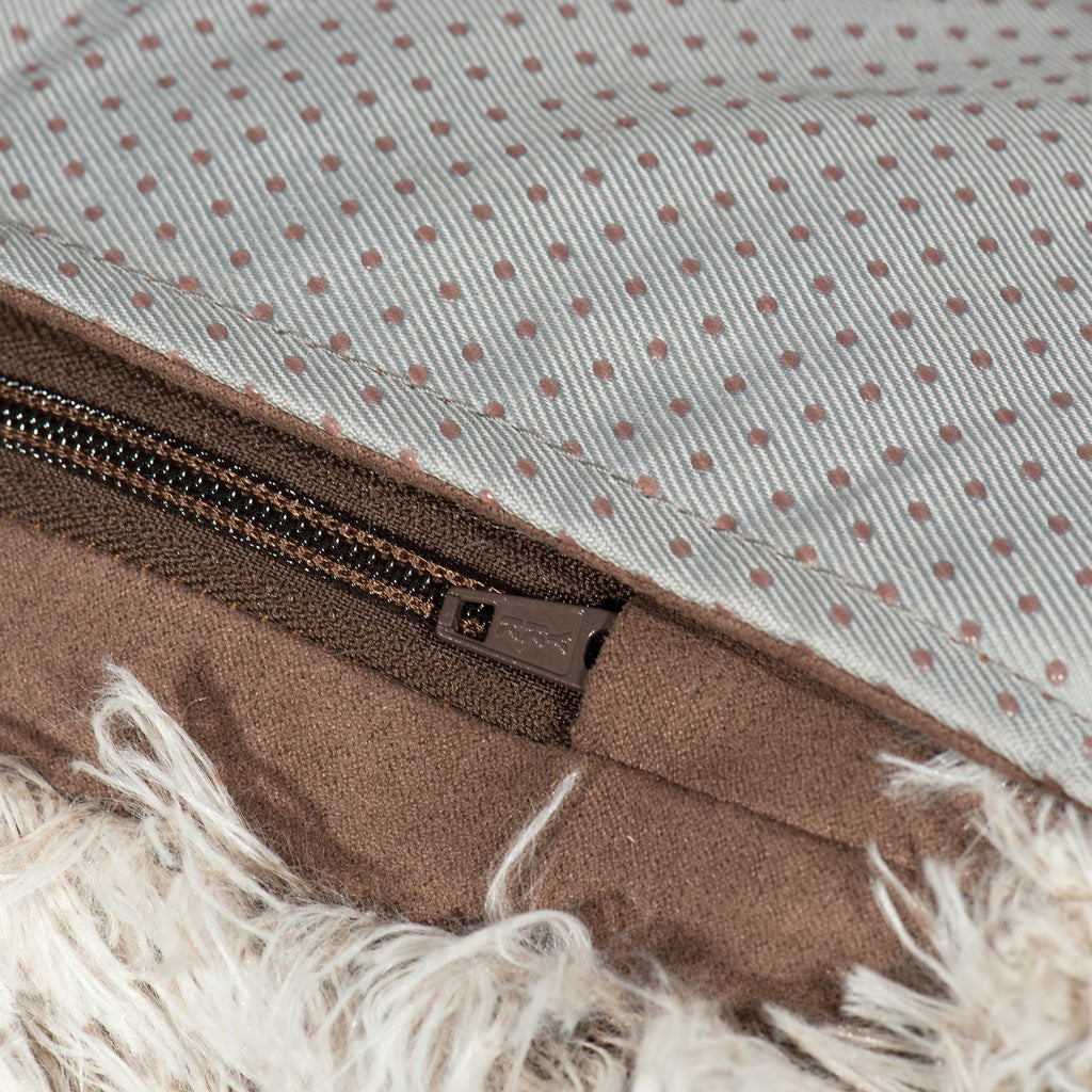 Brown zipper closure on gray dotted fabric inside faux-fur sofa protector
