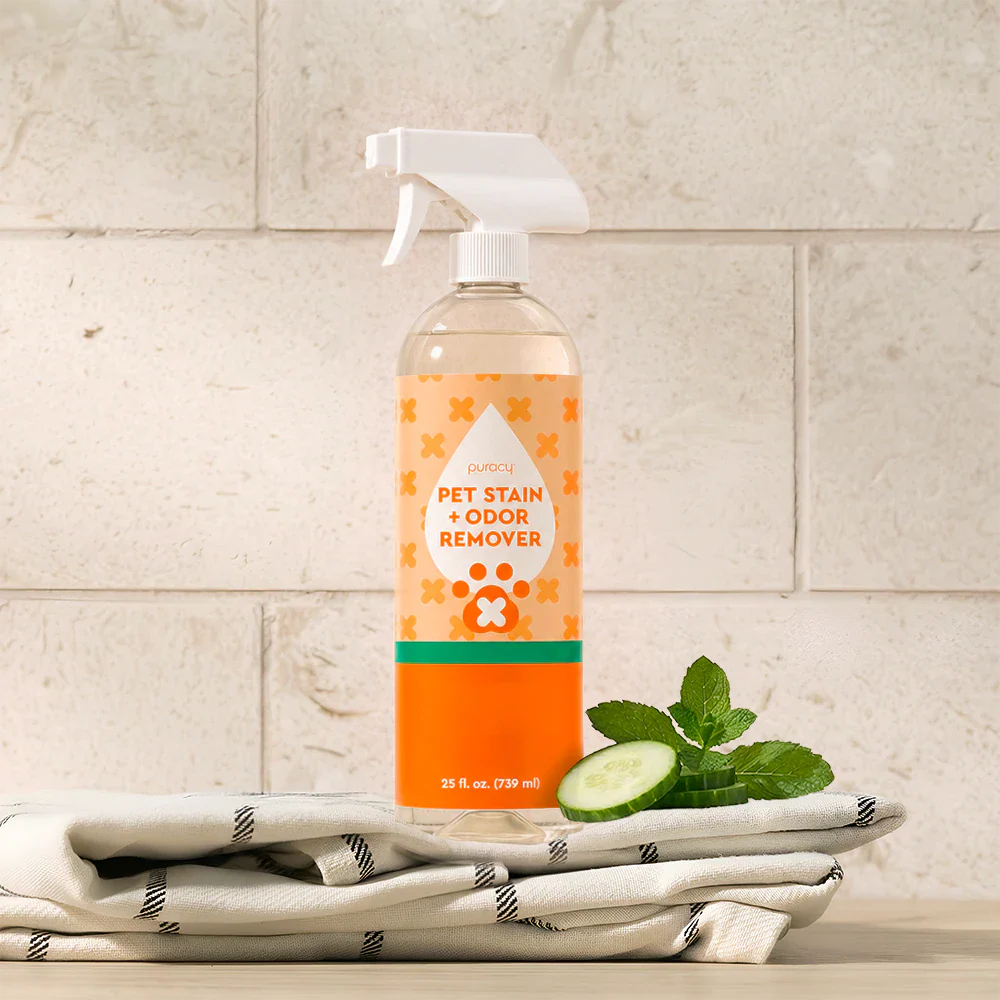 Orange-and-clear pet odor remover spray bottle with cucumber-mint scent, on folded towels