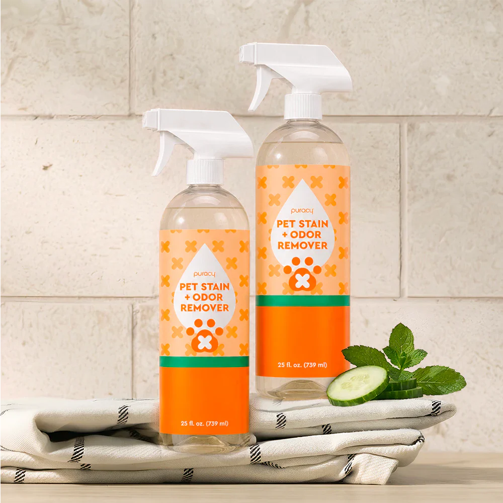 Two orange-and-clear pet odor remover spray bottles with cucumber-mint scent, on towels